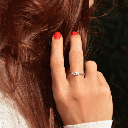 Photo portée d'un solitaire épaulé en or blanc palladié 18 carats serti d'un diamant central de 4mm et de deux diamants latéraux de 2mm