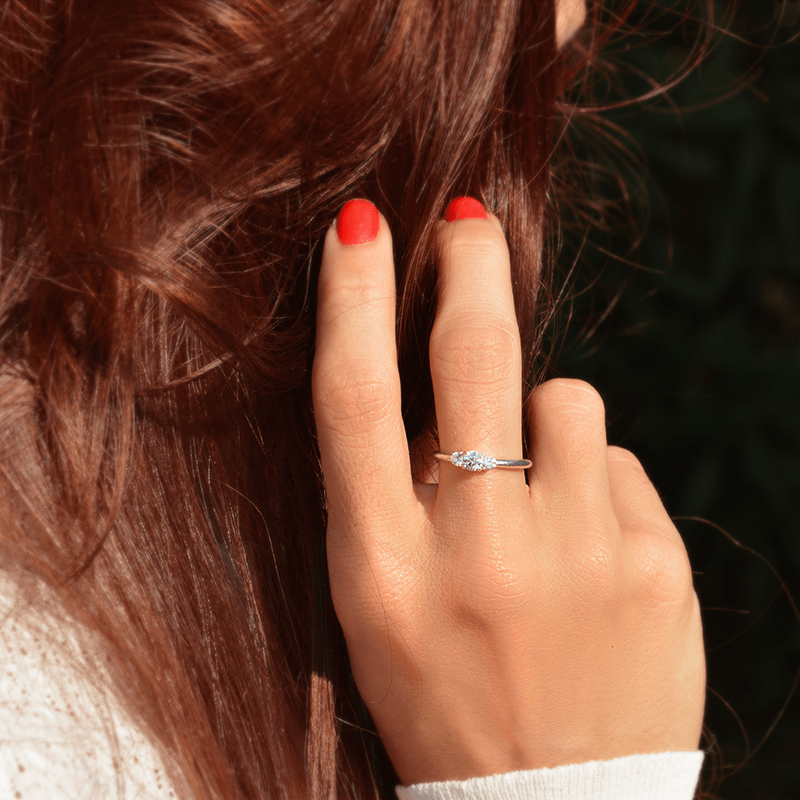 Photo portée d'un solitaire épaulé en or blanc palladié 18 carats serti d'un diamant central de 4mm et de deux diamants latéraux de 2mm