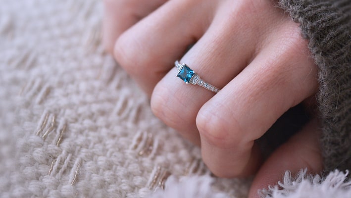 Photo portée d'un solitaire en or blanc palladié 18 carats serti d'une topaze blue london carrée /2| Faventine Joaillerie en ligne personnalisable